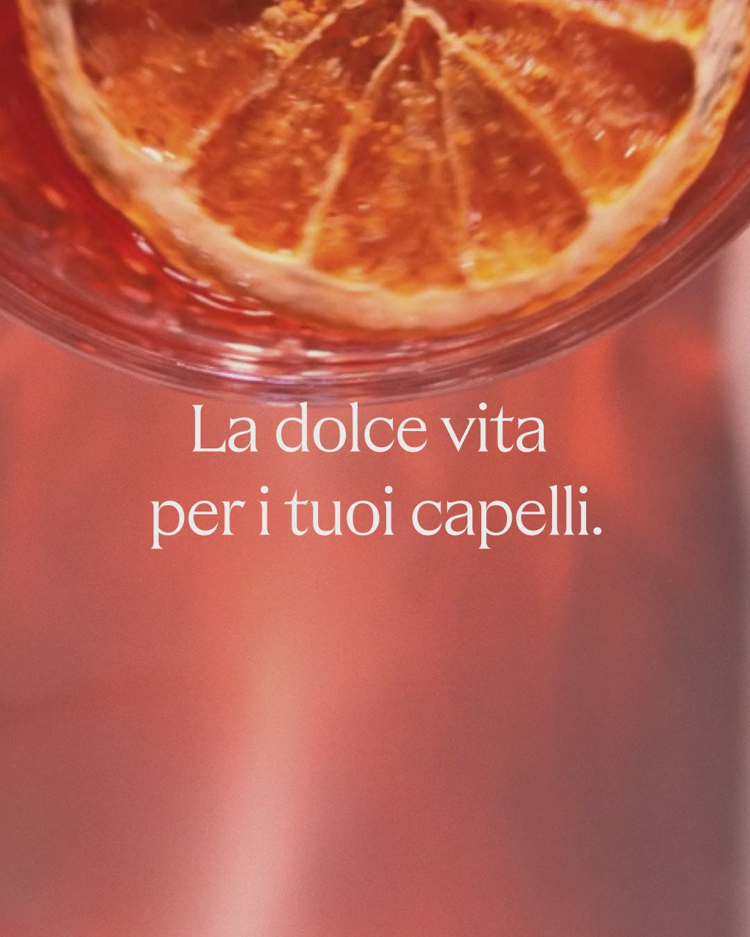 Donna con capelli tinti khadi AperòRed, un bicchiere con drink alcolico, una piazza al tramonto.